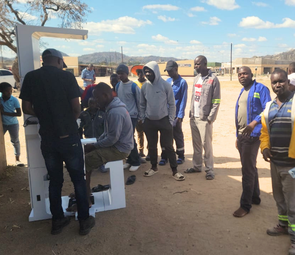 Health kiosk deployment in Africa, community members queuing for screening at an outdoor site